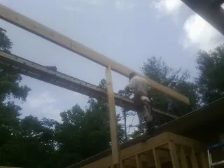 Carpenter setting a ridge beam over a new addition frame — Ice Dam Removal by Roofing Brothers in Sleepy Eye