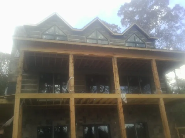 Dormers and porch framing on a large log home under construction — Roof Coating work by our crew in Sleepy Eye