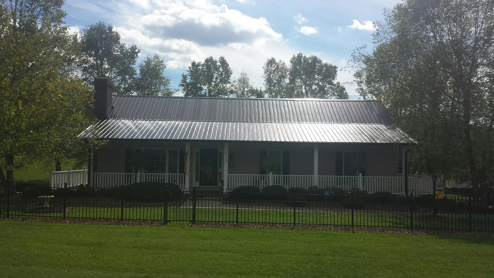 Gray metal roof on a brick ranch with a full width front porch — Gutter Guard Installation work by our crew in Sleepy Eye