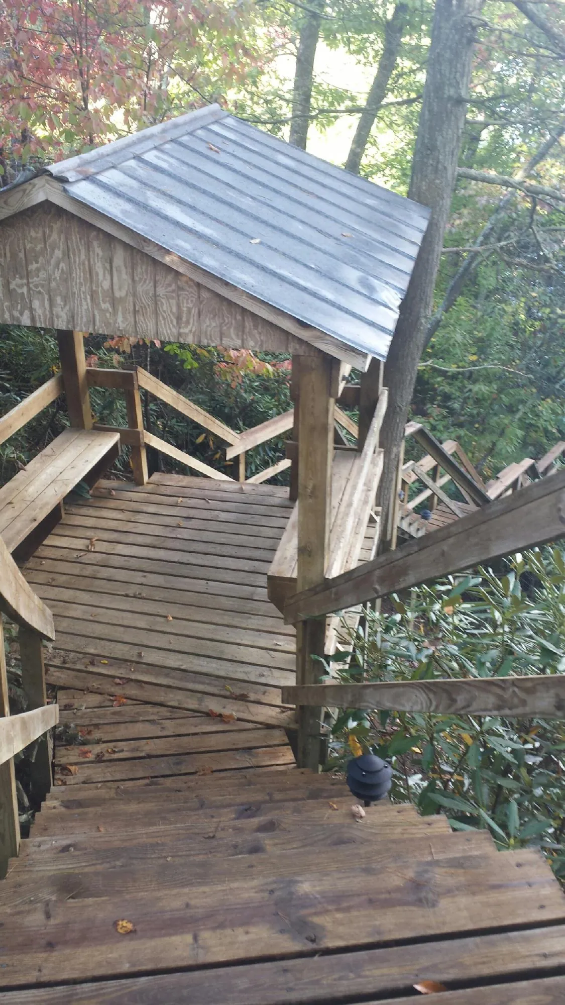 Metal roofed shelter over wooden steps on a wooded walkway — Skylight Repair & Installation work by our crew in Sleepy Eye