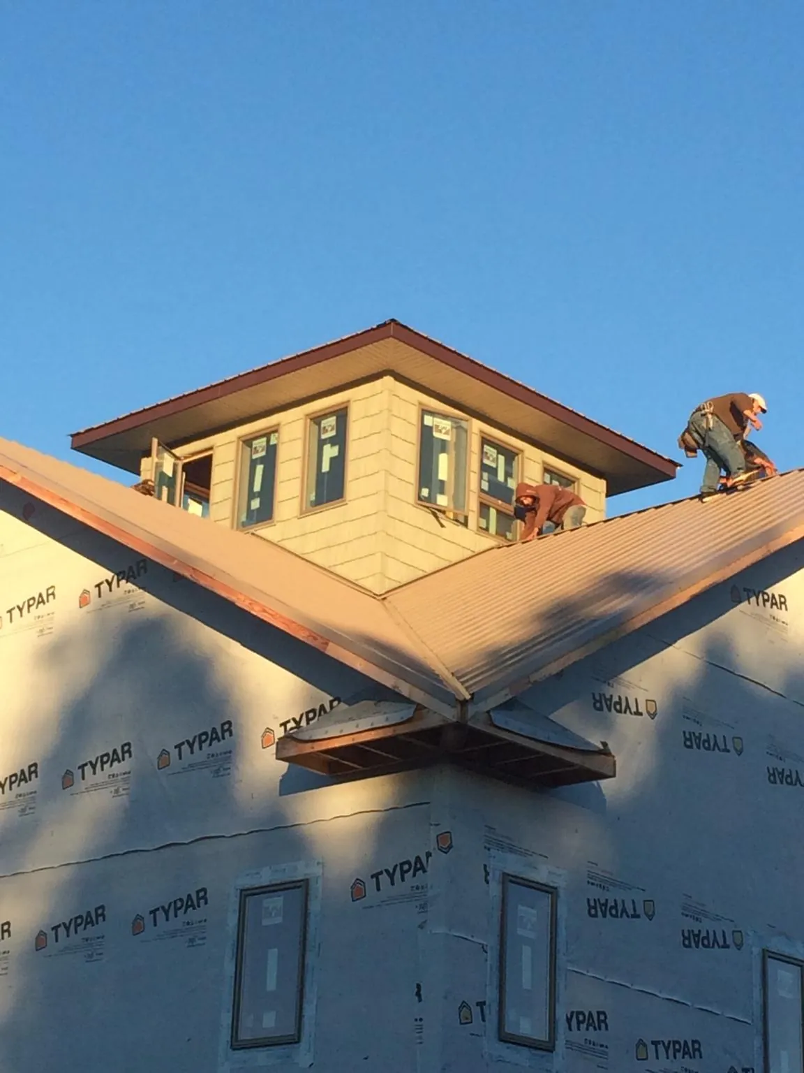 Roofers working around a rooftop cupola on a new metal roof at sunset — Roof Waterproofing in Sleepy Eye by Roofing Brothers